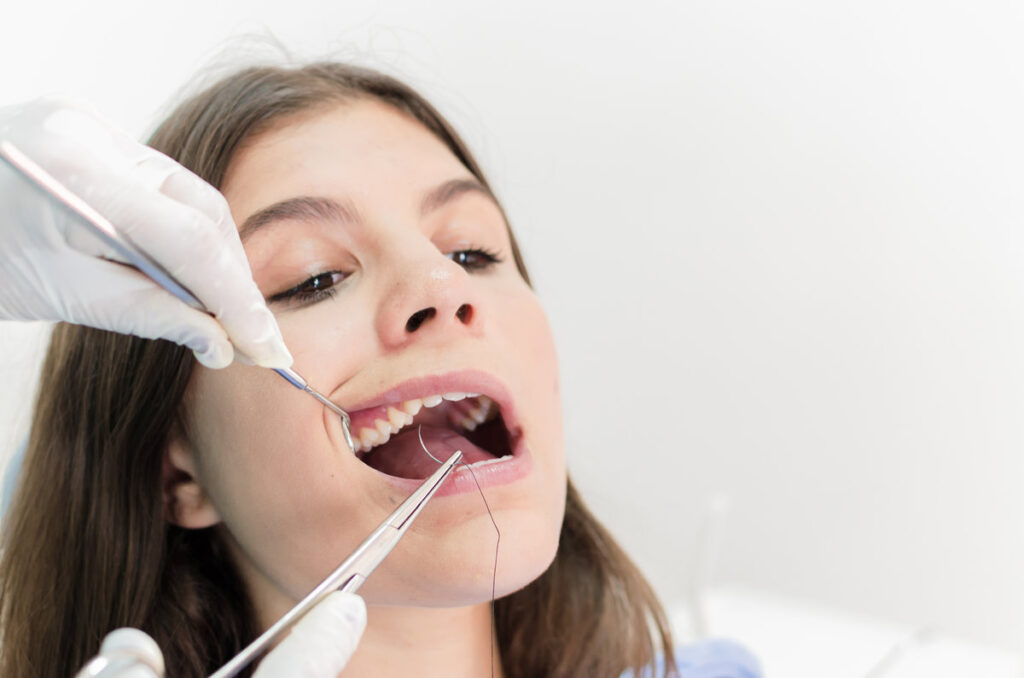 Young female patient takes a dental treatment in the dentist's office.