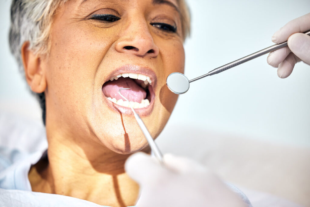 Senior woman, mouth and dentist check teeth, metal tools and hands with healthcare, toothache and dental surgery. Cleaning, wellness and health with oral care procedure, equipment and help with trust.