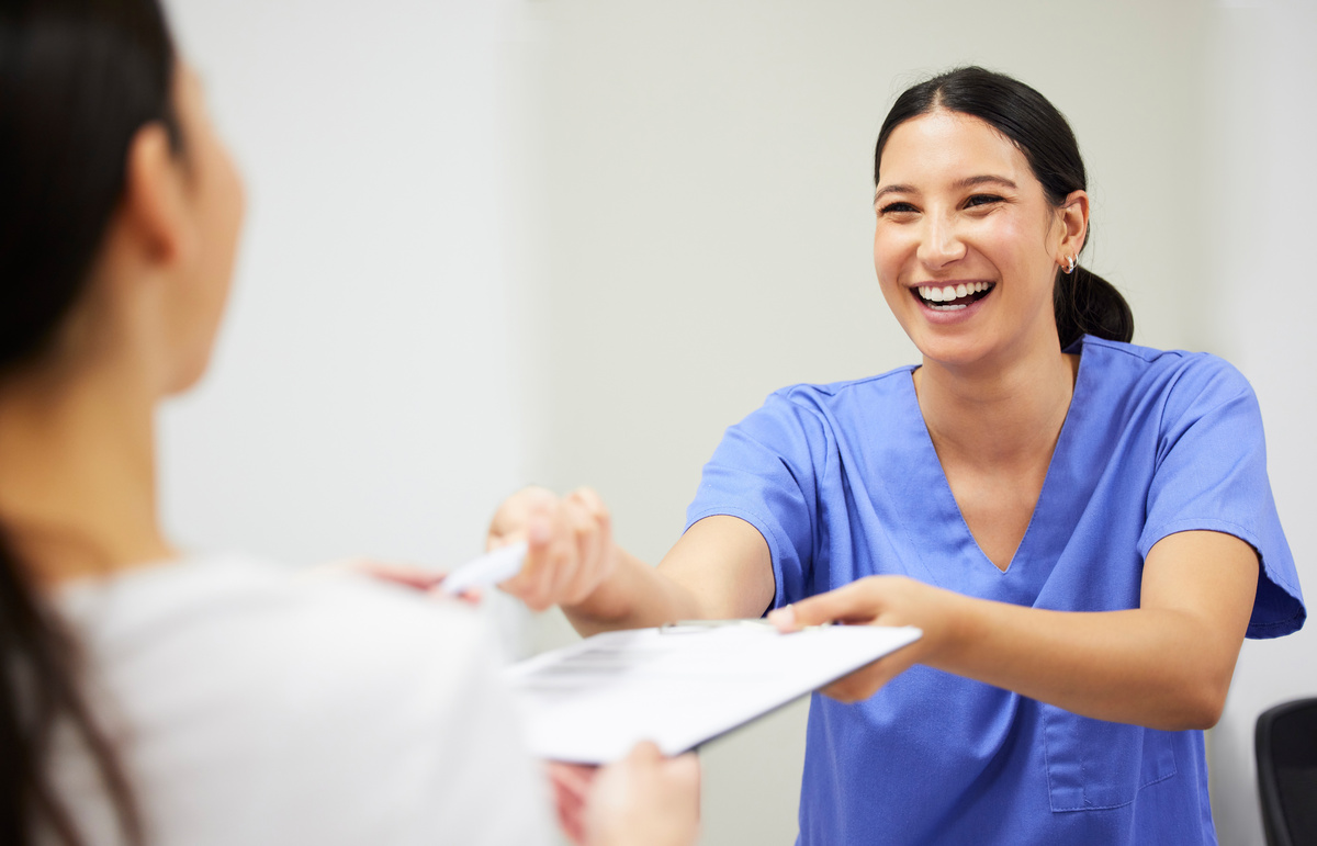 Documents, happy and a nurse helping a patient in the hospital during an appointment or checkup. Insurance form, smile and a medical assistant at a health clinic to help with check in or sign up.