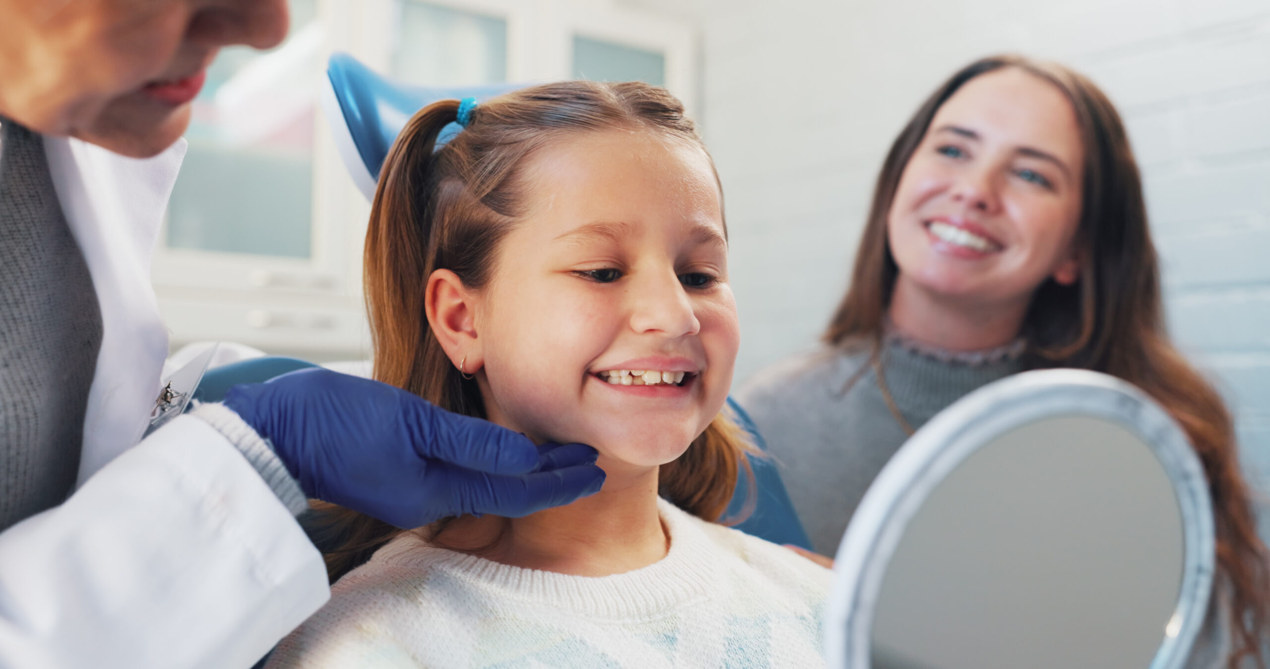 Happy child, dentist and mirror for oral hygiene or teeth health with advice from orthodontist. Girl, family or woman in clinic for dental care, wellness and results or education on cleaning of mouth.